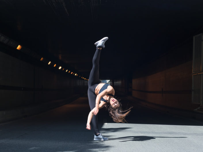 danseuse effactuant un jeté devant l'entrée d'un tunnel sur les berges à paris