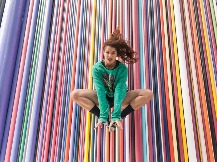 danseuse effectuant un saut devant un mur multicoloré à la défense en France