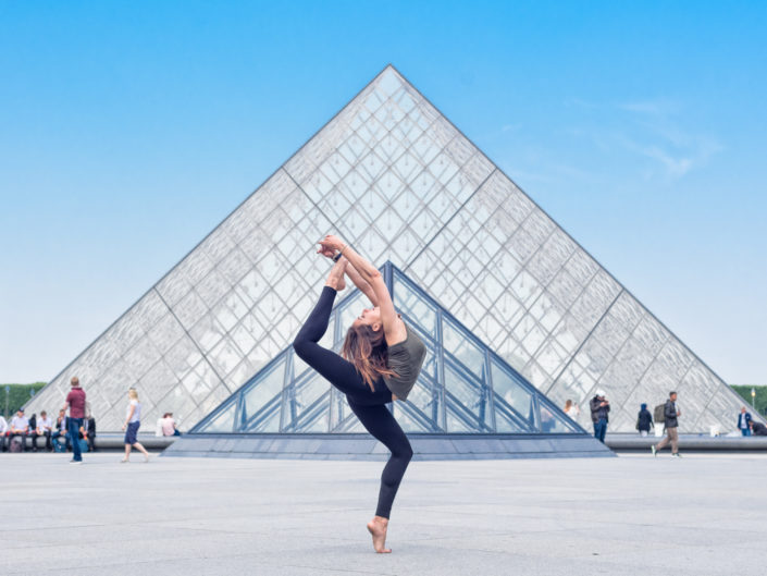 gymnaste bordelaise tenant la pose devant la pyramide du louvre