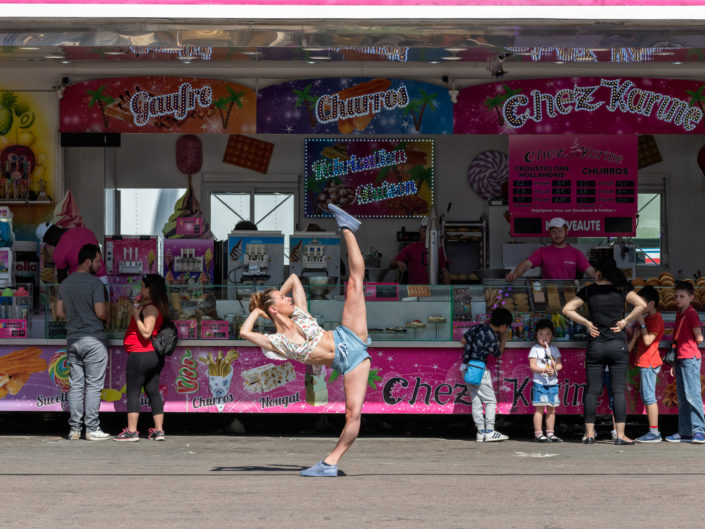 danseuse en souplesse devant un vendeur de barbe à papa à la foire du trône