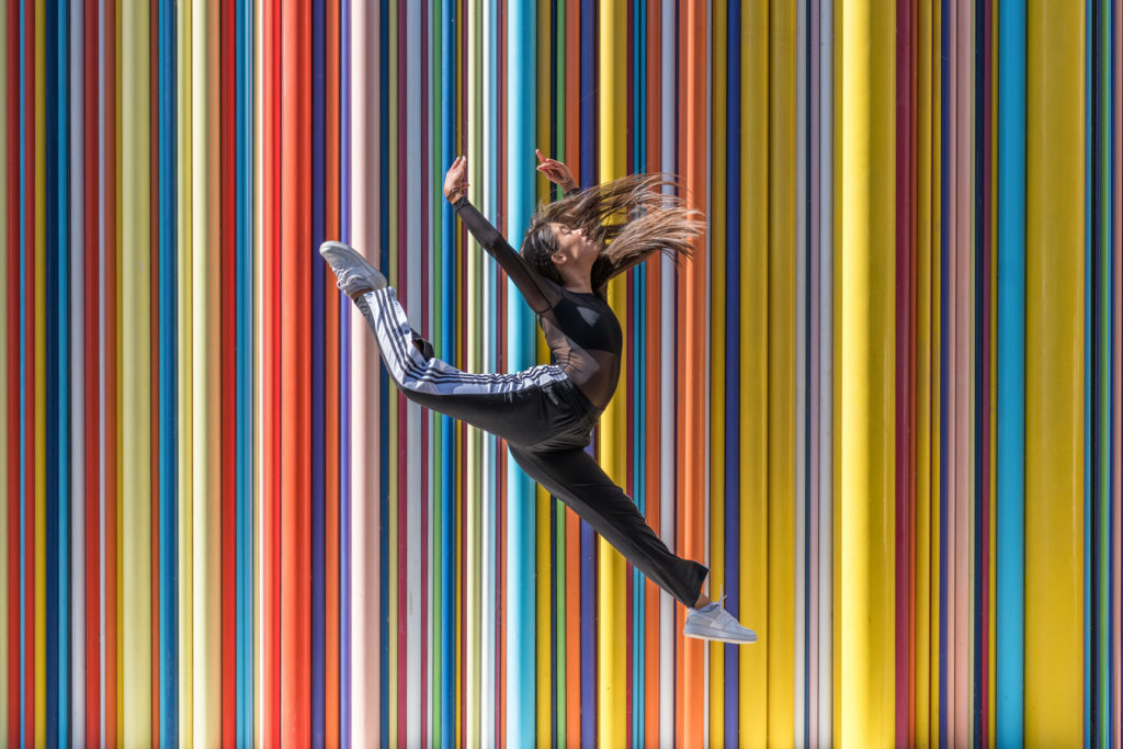 danseuse effectuant un saut devant le mur multicolor à courbevoie