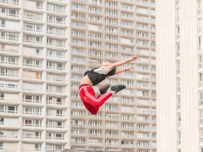 danseuse en levitation davant une barre de batiments