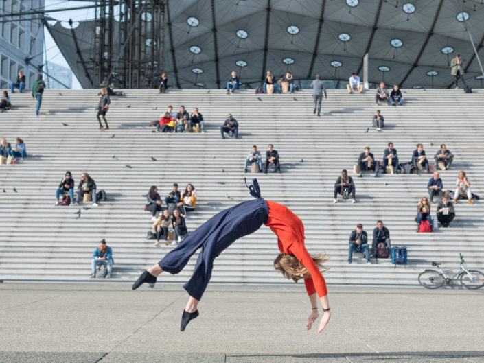 gymnaste effactuant un flip arriere devant arche de la defense