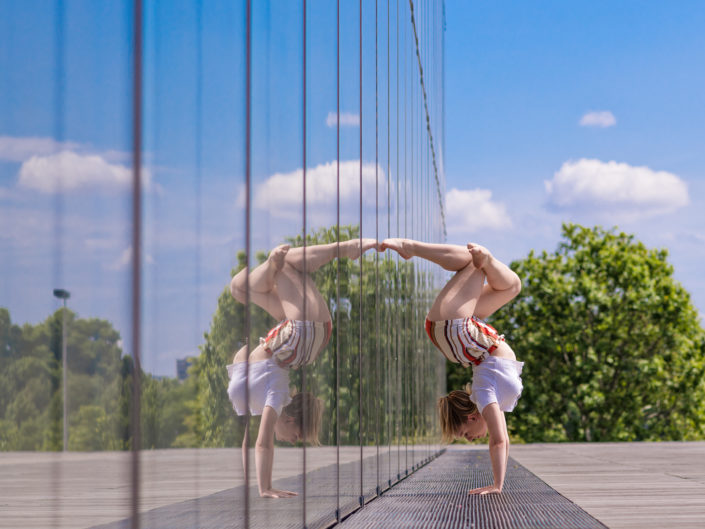 gymnaste lyonnaise effectuant un handstand contre une baie vitree de birhakeim