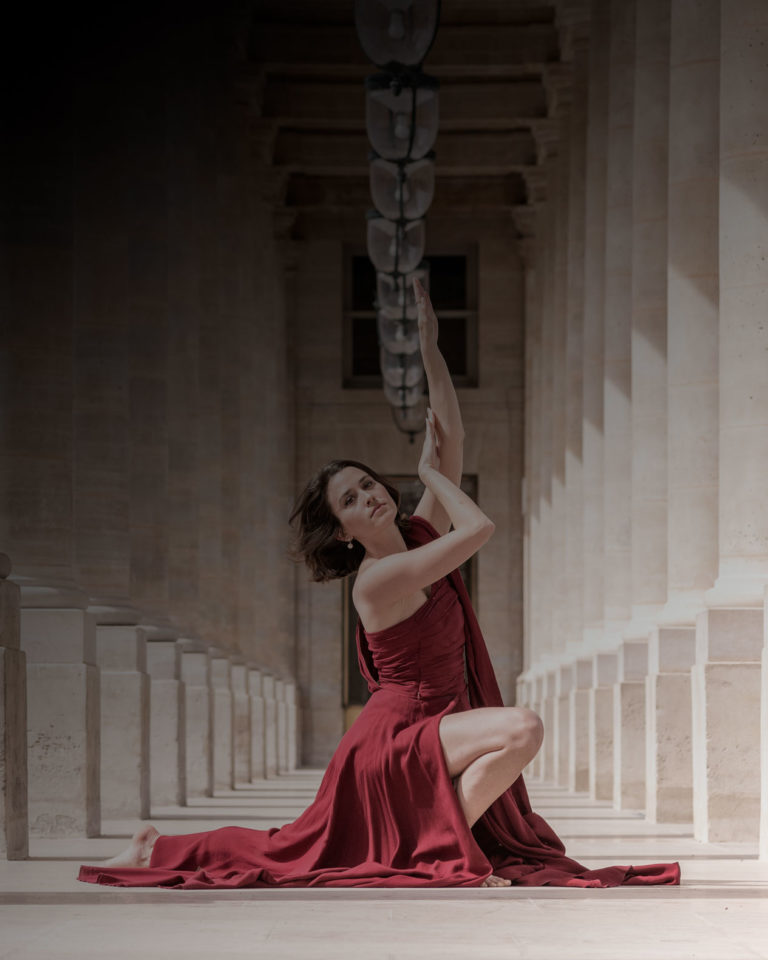 tirage vente danseuse avec une robe rouge entre les colonnes du palais royal à paris